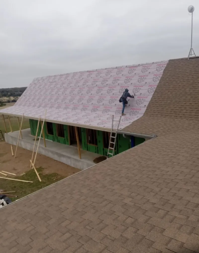 Worker preparing underlayment for a metal roof installation in Hampshire